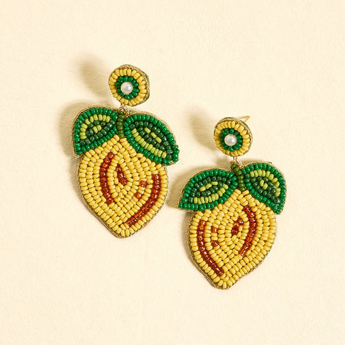 Lemon Beaded Earrings by The Darling Effect are vibrant, hand-beaded earrings featuring yellow, orange, and green beads shaped like lemons with leafy details, displayed on a light beige background.