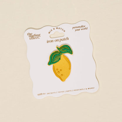 The Darling Effect’s Lemon Mix & Match Iron-On Patch features a yellow lemon with green leaves on a white card. Customize jackets, totes, hats, and more with this fun patch!.