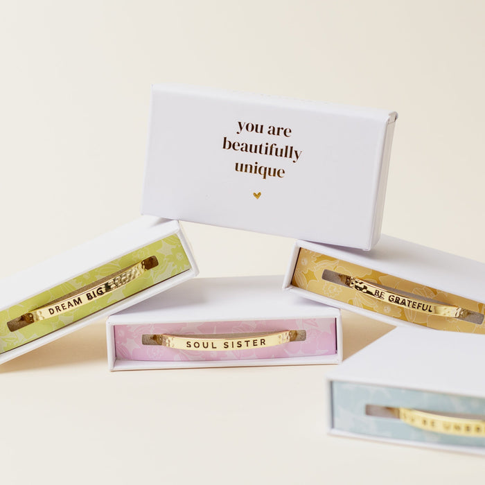 The Darling Effect’s Little Reminder Cuff, a mantra bracelet with an inspirational message, arrives in a gift box for an uplifting touch.