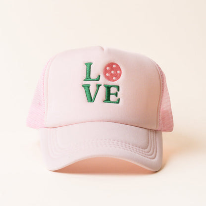 The LOVE Pickleball Trucker Hat by the-darling-effect features green embroidered "LOVE" lettering with a pink pickleball as the "O." A playful, stylish accessory for fans of trendy trucker hats.