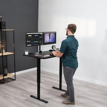 A man working at an ergonomic height adjustable standing desk.