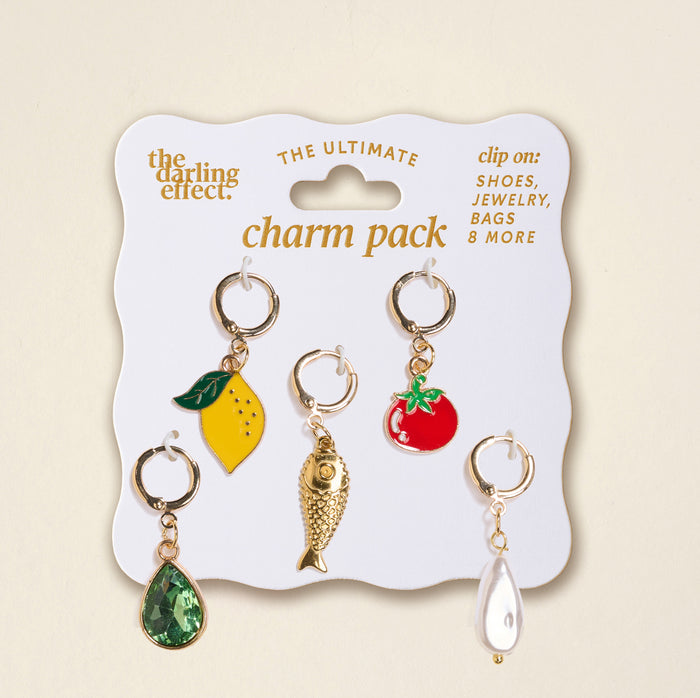 The Darling Effect’s Mediterranean Muse The Ultimate Charm Pack includes five gold keyring charms: yellow lemon with green leaf, red tomato, gold fish, green gem teardrop, and white pearl teardrop on a white card. Perfect for Scrunchie Charm Sets.