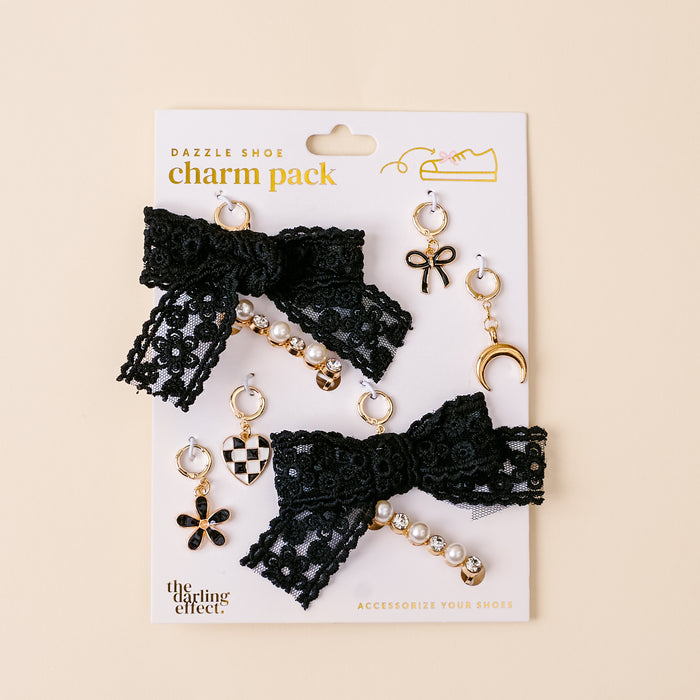 The Midnight Moment Dazzle Shoe Charm Pack by the-darling-effect includes black lace bows with gold, pearl and rhinestone accents, plus diverse charms like a checkered heart, flower, crescent moon, and bow—ideal for customizing your sneakers.
