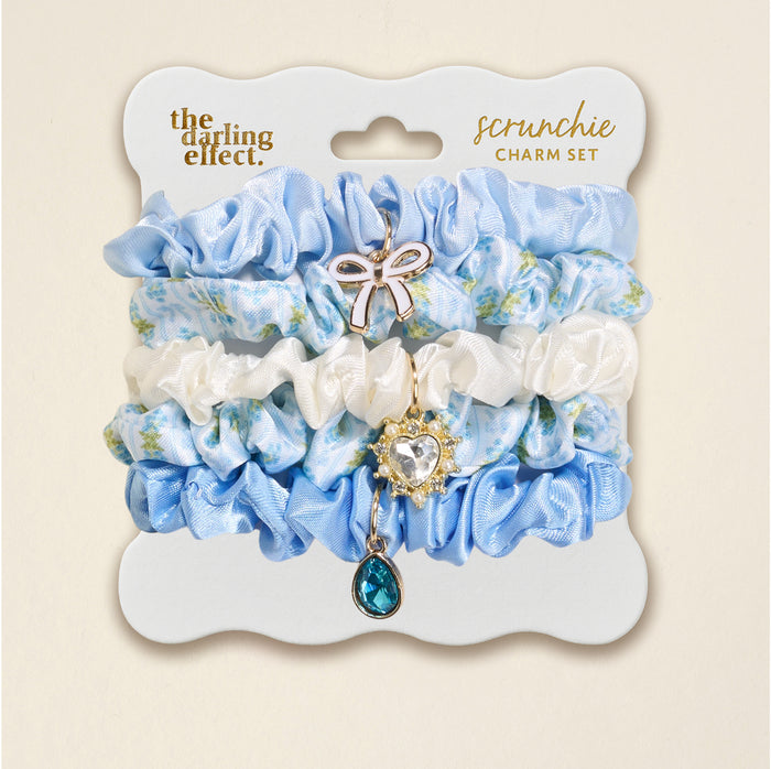 The Darling Effect Oh So Fancy Blue Scrunchie Charm Set includes 5 stylish blue, white, and floral satin scrunchies with gold bow, crystal heart, and teal teardrop charms, all on a scalloped card.