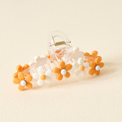 The Darling Effect’s Orange Game Day Daisy Claw Clip features white and orange daisy-shaped charms—perfect for adding a fun touch to your outfit or showing off your school colors.