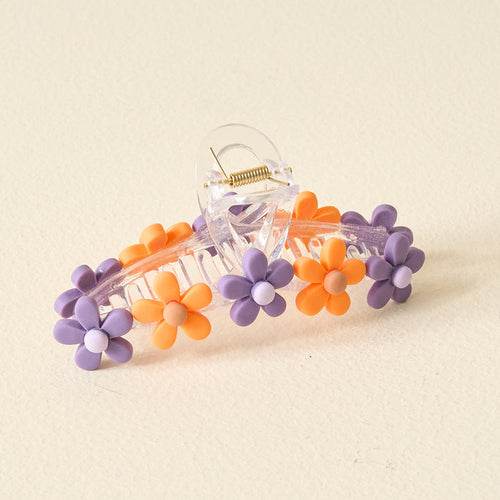 The Darling Effect’s Orange Purple Game Day Daisy Claw Clip features transparent design with alternating purple and orange daisies, perfect for showcasing school spirit or adding a fun touch to your game day style. Displayed on a plain light background.