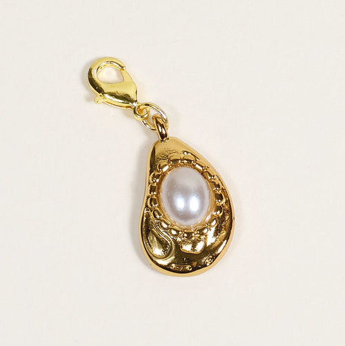 The Darling Effect's Oyster Jewelry Charm Gold features a lobster clasp and teardrop-shaped frame with intricate detailing around a central white pearl, shown on a plain light background—perfect for your charm bar.