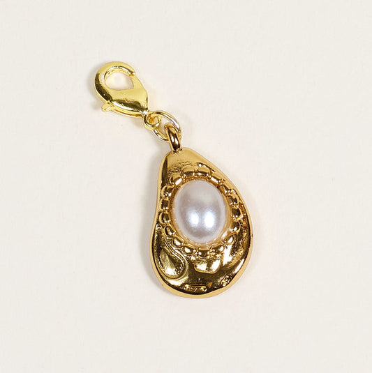 The Darling Effect's Oyster Jewelry Charm Gold features a lobster clasp and teardrop-shaped frame with intricate detailing around a central white pearl, shown on a plain light background—perfect for your charm bar.