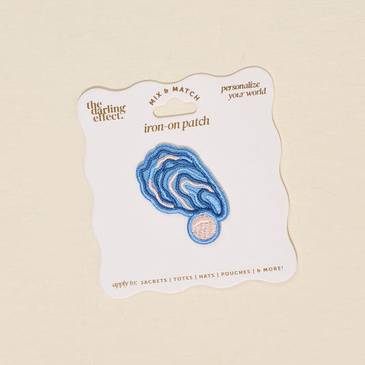 The Darling Effect's Oyster Mix & Match Iron-On Patch features a blue and pink abstract wavy design on a white backing card. Easily customize your style with this unique, colorful patch.
