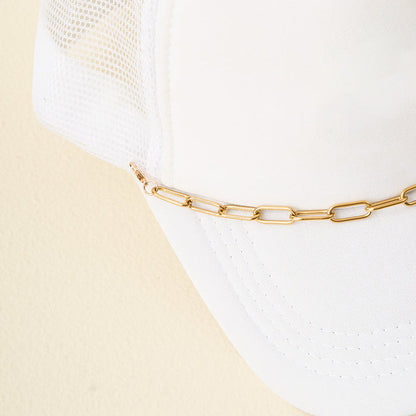 A close-up of The Darling Effect's Paperclip Chain-Gold Trucker Hat Chain attached to a white mesh trucker hat, displayed against a light beige background.