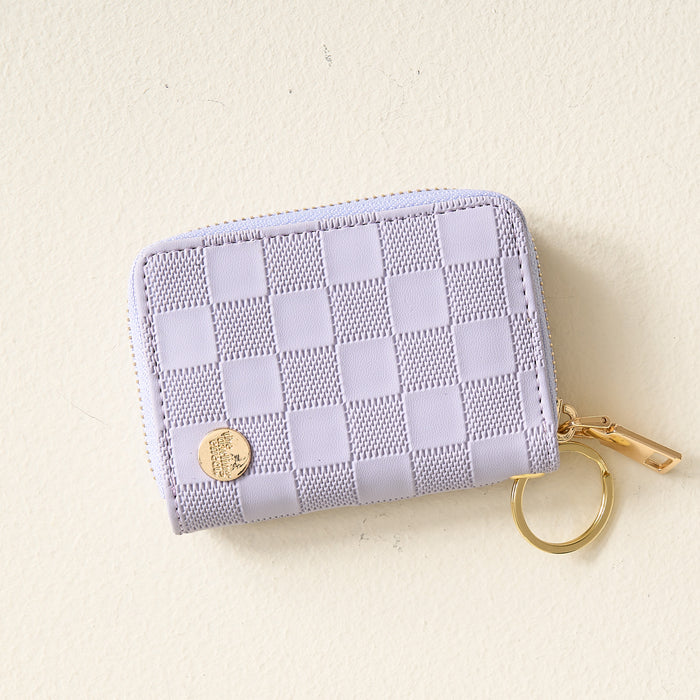 The Darling Effect Periwinkle Check Zip Around Wallet, featuring a gold zipper, convenient card slots, and a handy keyring, is shown on a light beige surface.