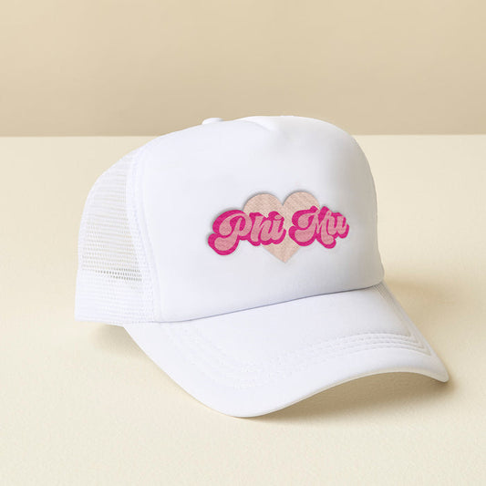 The Darling Effect Phi Mu White Trucker Hat features a pink heart and "Phi Mu" in pink script on the front, displayed on a light cream surface with a beige background.