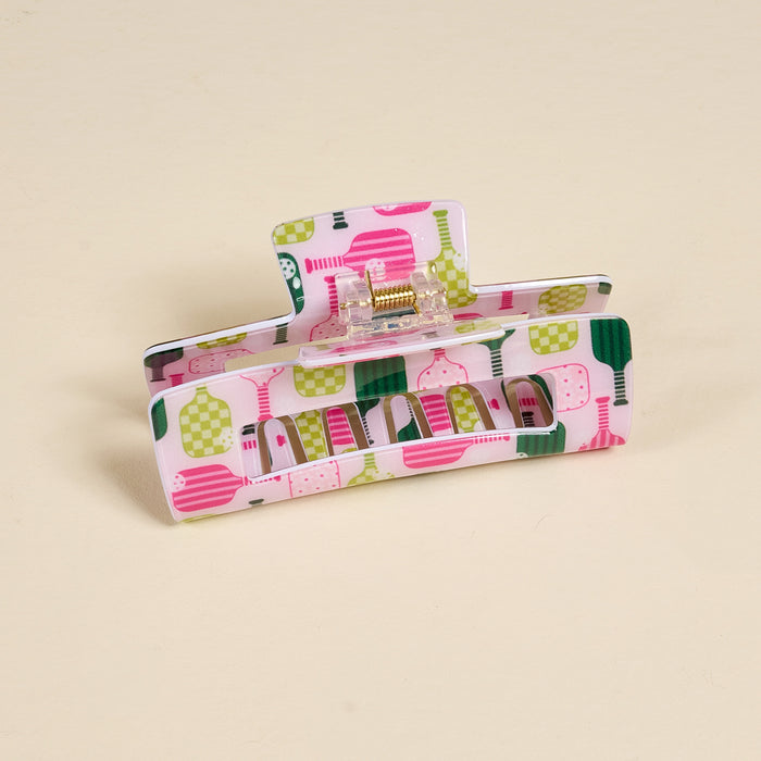 The Pickleball Party Claw Clip by the-darling-effect is a rectangular hair accessory featuring a colorful pink, green, and white abstract pattern, shown on a light beige background—perfect for adding flair to any look.