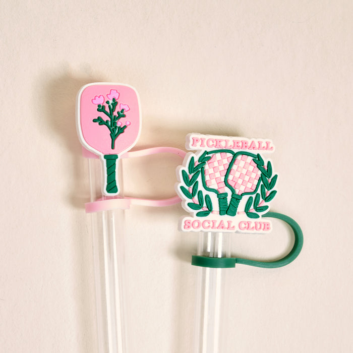 The Darling Effect’s Pickleball Social Club Straw Topper Set includes two decorative straw toppers: a pink paddle with flowers and a green paddle with “Pickleball Social Club” and laurel leaves, each with flexible bands for easy use.