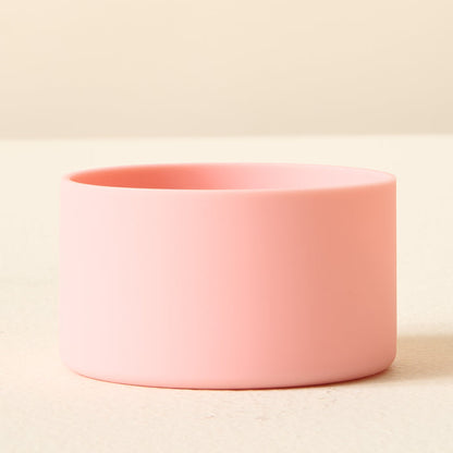 The Darling Effect Pink Tumbler Silicone Boot sits on a pale yellow surface against a cream background, providing a stylish no-slip grip and sturdy tumbler protection in one.