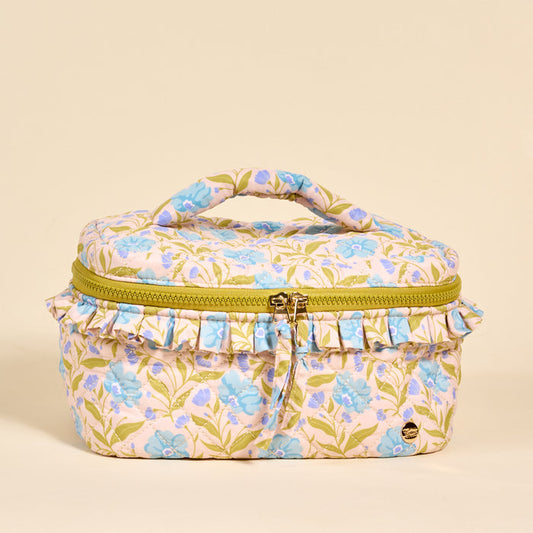 The Darling Effect’s Poppin' Petals Aqua Glam & Go Quilted Cosmetic Bag features a floral design, green leaves, light blue blooms, ruffled trim, a yellow zipper, and top handle—all on a beige background.
