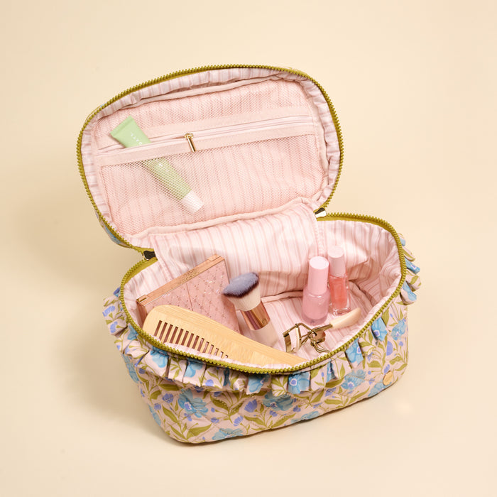 The Darling Effect Poppin' Petals Aqua Glam & Go Quilted Cosmetic Bag opens to reveal a pink lining and holds a makeup brush, comb, eyelash curler, makeup palette, and two nail polish bottles.
