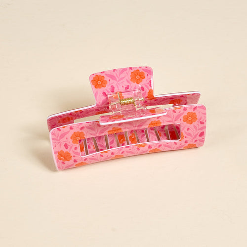 The Darling Effect’s Poppin' Petals Hot Pink Claw Clip features a pink base, orange floral print, and cream accents—delivering a strong hold and bold style as an eye-catching hair accessory.