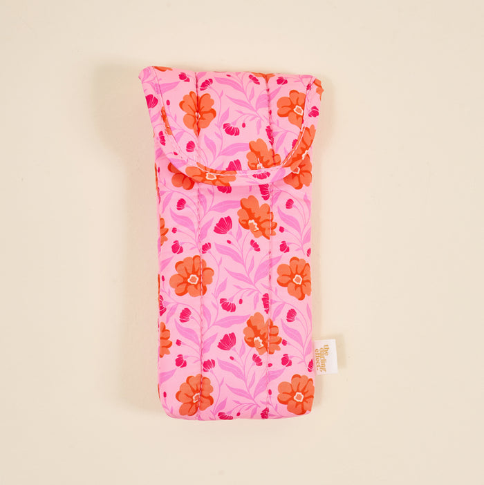 The Darling Effect’s Poppin' Petals Hot Pink Puffy Sunglasses Case features a quilted design with orange flowers, pink leaves, and a magnetic flap closure to keep your eyeglasses secure.