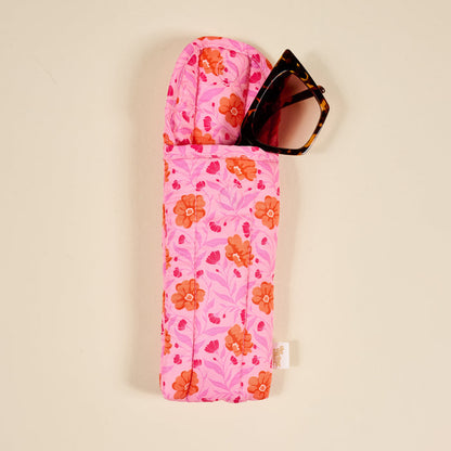 The Darling Effect’s Poppin' Petals Hot Pink Puffy Sunglasses Case features a bold orange and pink floral print, quilted design, and magnetic flap closure. Shown here with tortoiseshell sunglasses inside.