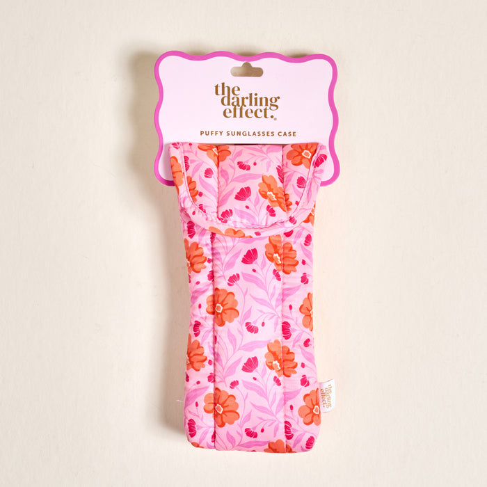 The Darling Effect Poppin' Petals Hot Pink Puffy Sunglasses Case features an orange and pink floral pattern, quilted design, and magnetic flap closure for extra style and protection.