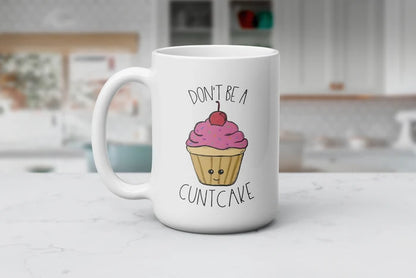 Pretty Frosting, Petty Thoughts white ceramic coffee mug featuring a smiling cupcake with pink frosting, colorful sprinkles and a cherry with the phrase “Don’t Be a Cuntcake,” available in 11 oz and 15 oz sizes.