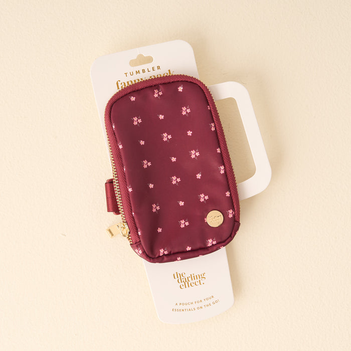 The Darling Effect’s Pretty Posies Plum Tumbler Fanny Pack features a maroon pouch with pink floral pattern and gold zipper—water-resistant to keep your essentials secure on the go!.