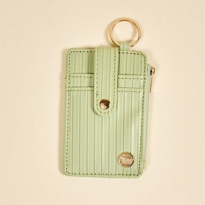 The Darling Effect Sage Ripple Ridge Keychain Wallet features a pastel green hue, vertical ribbed texture, gold snap and zipper, zippered coin holder, and multiple card slots for convenience.