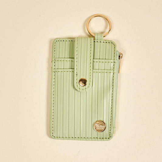 The Darling Effect Sage Ripple Ridge Keychain Wallet features a pastel green hue, vertical ribbed texture, gold snap and zipper, zippered coin holder, and multiple card slots for convenience.