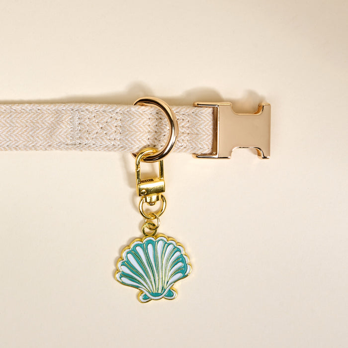 The Darling Effect’s Seashell Pawfect Collar Charm features a blue and white enamel seashell with a gold keychain, perfect for adding coastal flair to your pet’s collar or pairing with other charms.