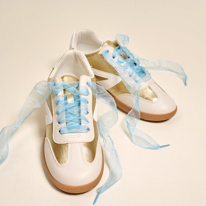 A pair of white and gold sneakers featuring The Darling Effect’s Sheer Blue Step It Up Shoelaces are displayed on a plain off-white surface.