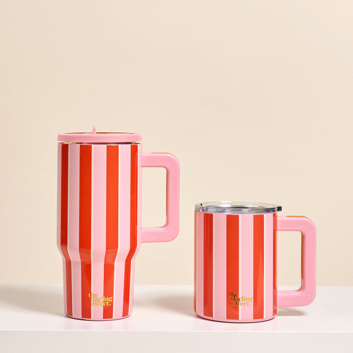 Two Sicily Stripes Pink 14 oz Insulated Mugs by The Darling Effect sit side by side on a white surface. Both feature vertical red and pink stripes with gold text, large handles, and clear lids; one mug is taller than the other.