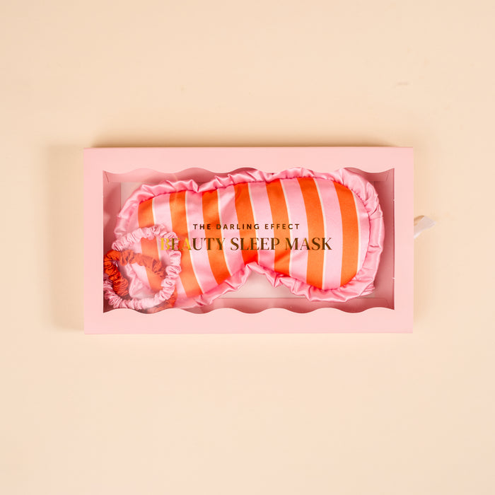 The Darling Effect Sicily Stripes Pink Beauty Sleep Mask features pink and orange stripes, ruffled edges, and a matching elastic band. Presented in a pink box, it’s perfect to pair with your favorite satin scrunchies.