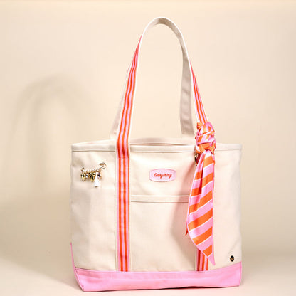 The Darling Effect's Sicily Stripes Pink The Darling Canvas Tote Bag features a white canvas body, bright pink base, pink accents, striped handles, a stylish scarf on one handle, gold charm on the pocket, and a spacious interior.