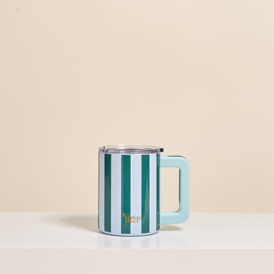 The Darling Effect's Sicily Stripes Teal 14 oz Insulated Mug, featuring green and white stripes with a light blue handle and lid, sits on a white shelf against a cream background—ideal for fans of stylish insulated mugs.