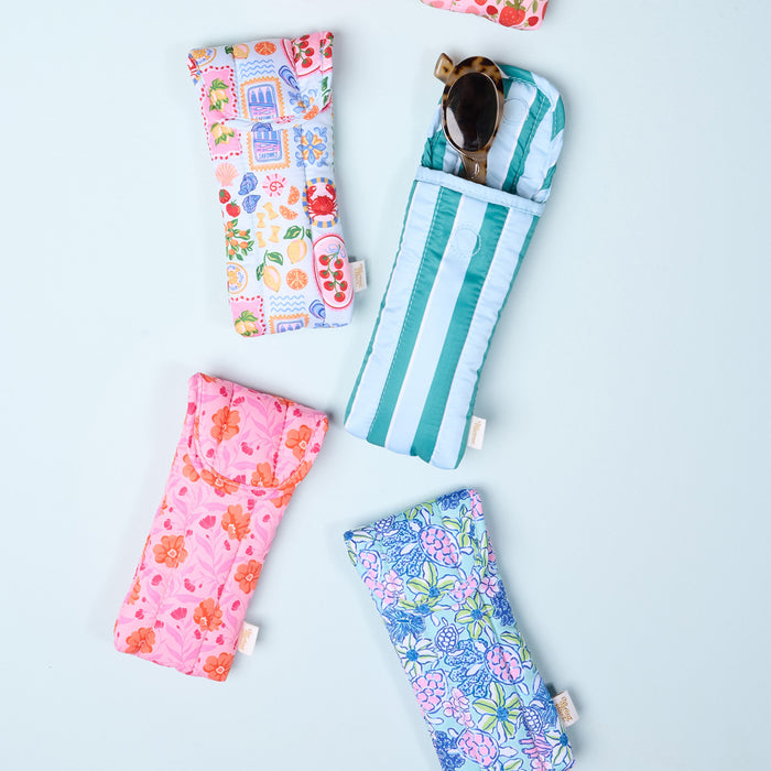 Five vibrant Sicily Stripes Teal Puffy Sunglasses Cases by The Darling Effect are arranged on a light blue background, each offering stylish eyeglasses protection—one is partially open, revealing sunglasses beneath its magnetic flap closure.