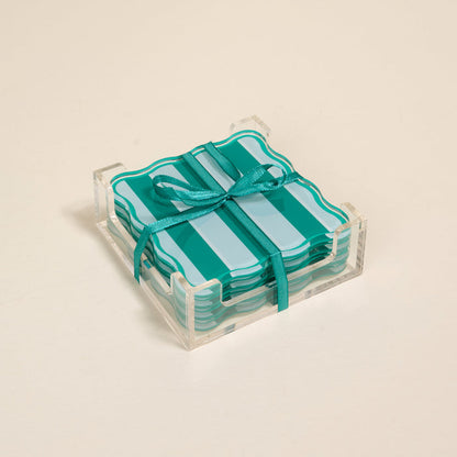 The Darling Effect Sicily Stripes Teal Table Talk Acrylic Coaster Set features heat-resistant, teal and turquoise striped coasters with scalloped edges in a clear holder, tied with a teal ribbon—ideal for chic table décor.
