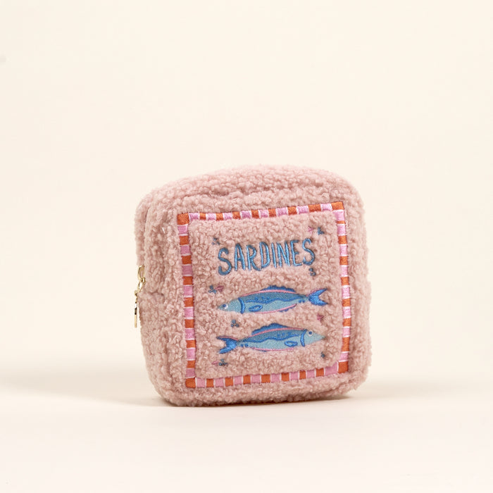 The Darling Effect Square Sardines Teddy Pouch is a small, pink, sherpa pouch with a fuzzy texture, side zipper, and embroidered patch featuring two blue sardines and the word "SARDINES.