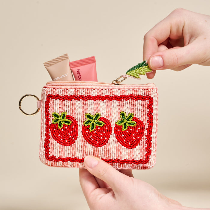 The Darling Effect's Strawberries Handcrafted Beaded Pouch features three strawberry designs and fits perfectly in two hands. Unzipped, it reveals storage space for essentials like two lip balm tubes.