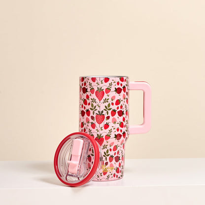 The Darling Effect’s Strawberry Fields 20 oz Lifestyle Flip Straw Tumbler in tall pink features a floral and strawberry pattern, shown upright on a white surface with its matching pink lid beside it and a beige background.