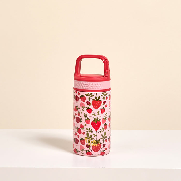 The Darling Effect’s Strawberry Fields 6 oz Lil' Bitty Bottle features a pink petite design with a red handle, strawberry and green leaf accents—an adorable hydration companion for travel, shown on a white surface against a light beige background.