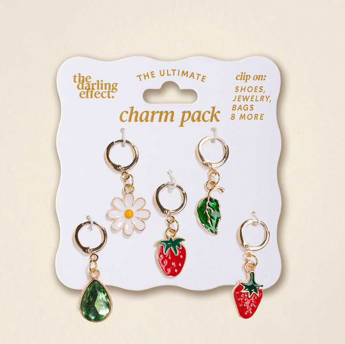 A pack of five gold charm clips—green teardrop, white daisy, green leaf, and two red strawberries—displayed on a Strawberry Meadow The Ultimate Charm Pack card by The Darling Effect. Perfect to pair with Scrunchie Charm Sets for extra flair!.