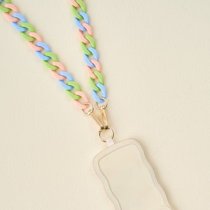 The Darling Effect’s Tri Lively Hold the Phone Crossbody Chain with pastel pink, blue, and green links clips to a beige, wavy-edged badge holder with gold clasps and is displayed on a light cream background.