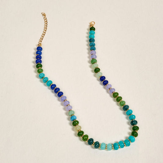 The Darling Effect's True Blues Stone Candy Necklace features blue, green, and light purple gradient stone beads with a gold chain and clasp—a playful jewelry accent for any outfit.