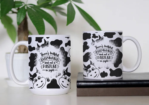 Udderly Over the Bullshit white ceramic coffee mug featuring black-and-white cow print, cartoon cows and the saying there's bullshit everywhere and not a pasture in sight.