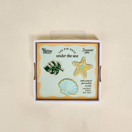 The Darling Effect’s Under the Sea The Pin Pack features three enamel pins—a monstera leaf, starfish, and scallop shell—ideal for collectors and accessory lovers.