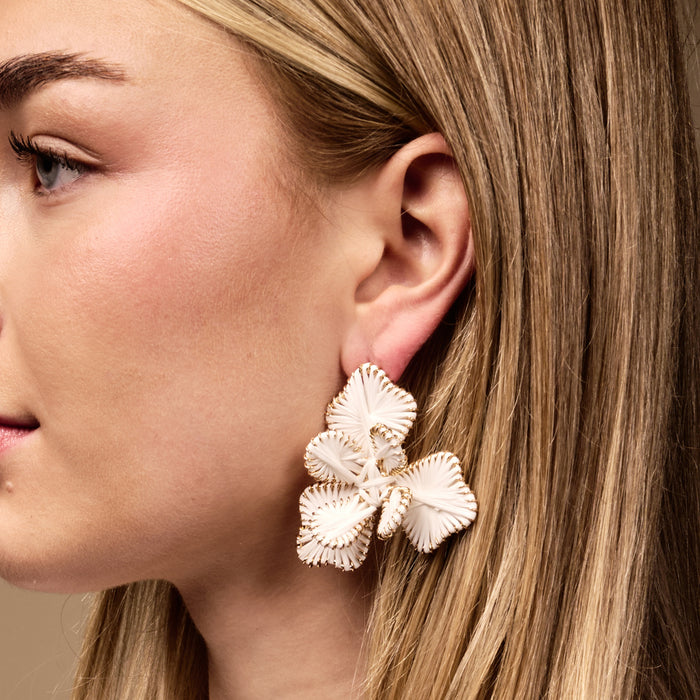 Close-up of a woman's face wearing The Darling Effect's White Main Character Earrings—large, lightweight, floral-shaped earrings with gold trim, perfect for everyday boho style.