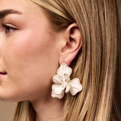 Close-up of a woman's face wearing The Darling Effect's White Main Character Earrings—large, lightweight, floral-shaped earrings with gold trim, perfect for everyday boho style.
