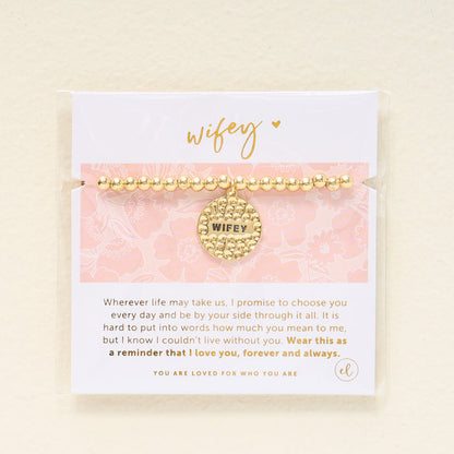 The Darling Effect’s Wifey Beaded Charm Bracelet features gold beads and a round “Wifey” charm, presented on a floral card with an inspirational quote—making it a meaningful gift for someone special.
