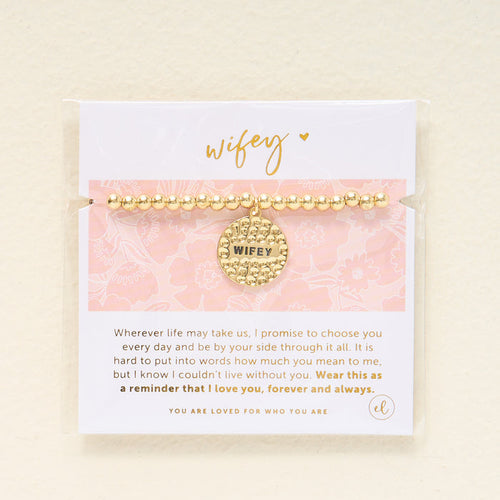 The Darling Effect’s Wifey Beaded Charm Bracelet features gold beads and a round “Wifey” charm, presented on a floral card with an inspirational quote—making it a meaningful gift for someone special.